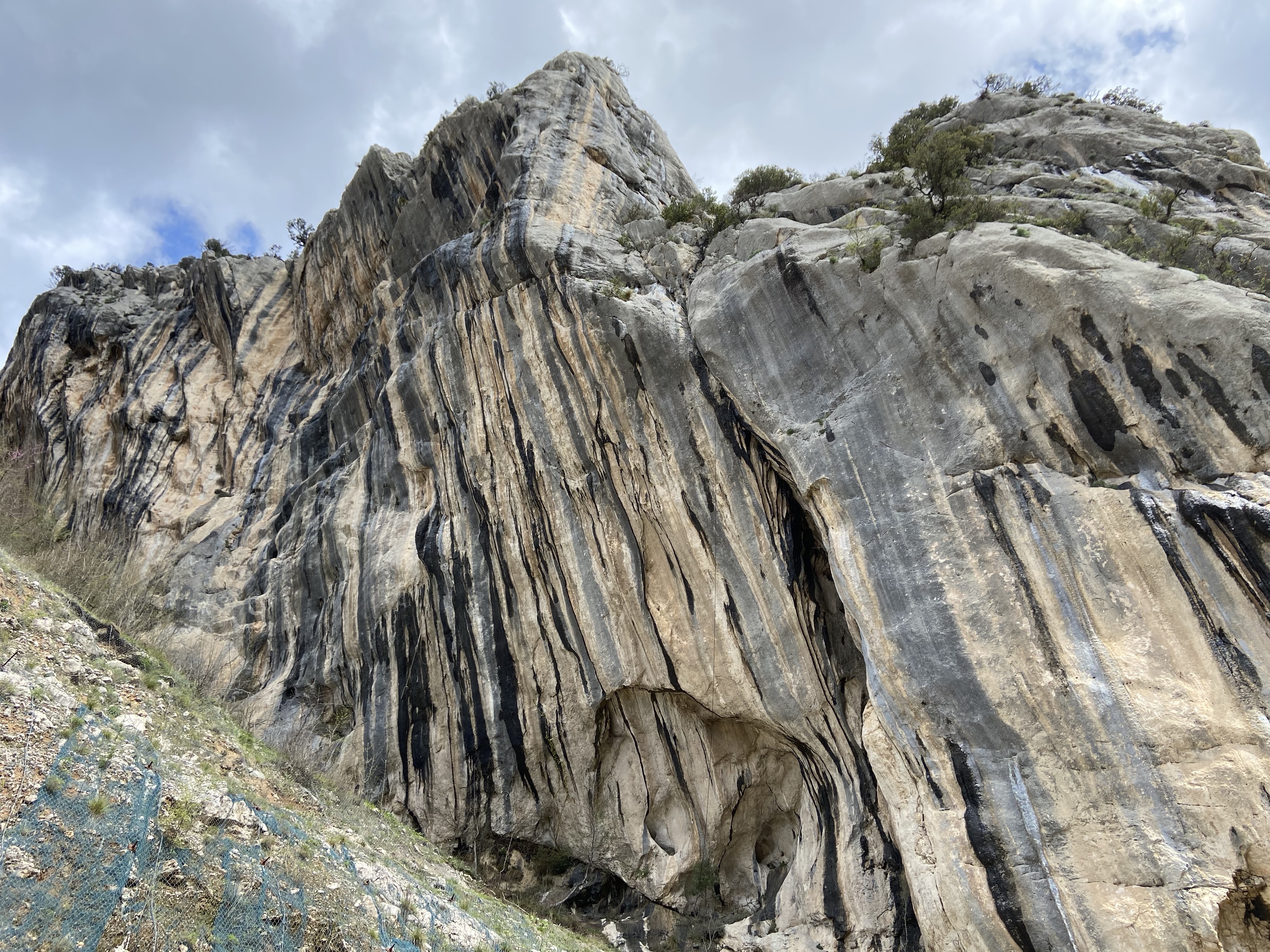 Imposing crag with wet, grey and white limestone streaks. 