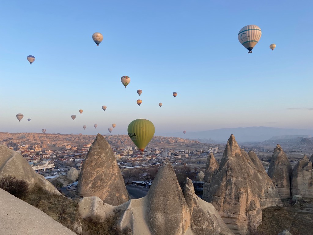 Early morning sky with many hot air ballons throughout the sky with the interesting pillars. It is something straight out of a sci fi film!
