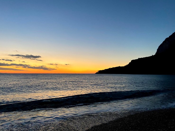 Orange sunrise with the waves lapping at Olympos beach.