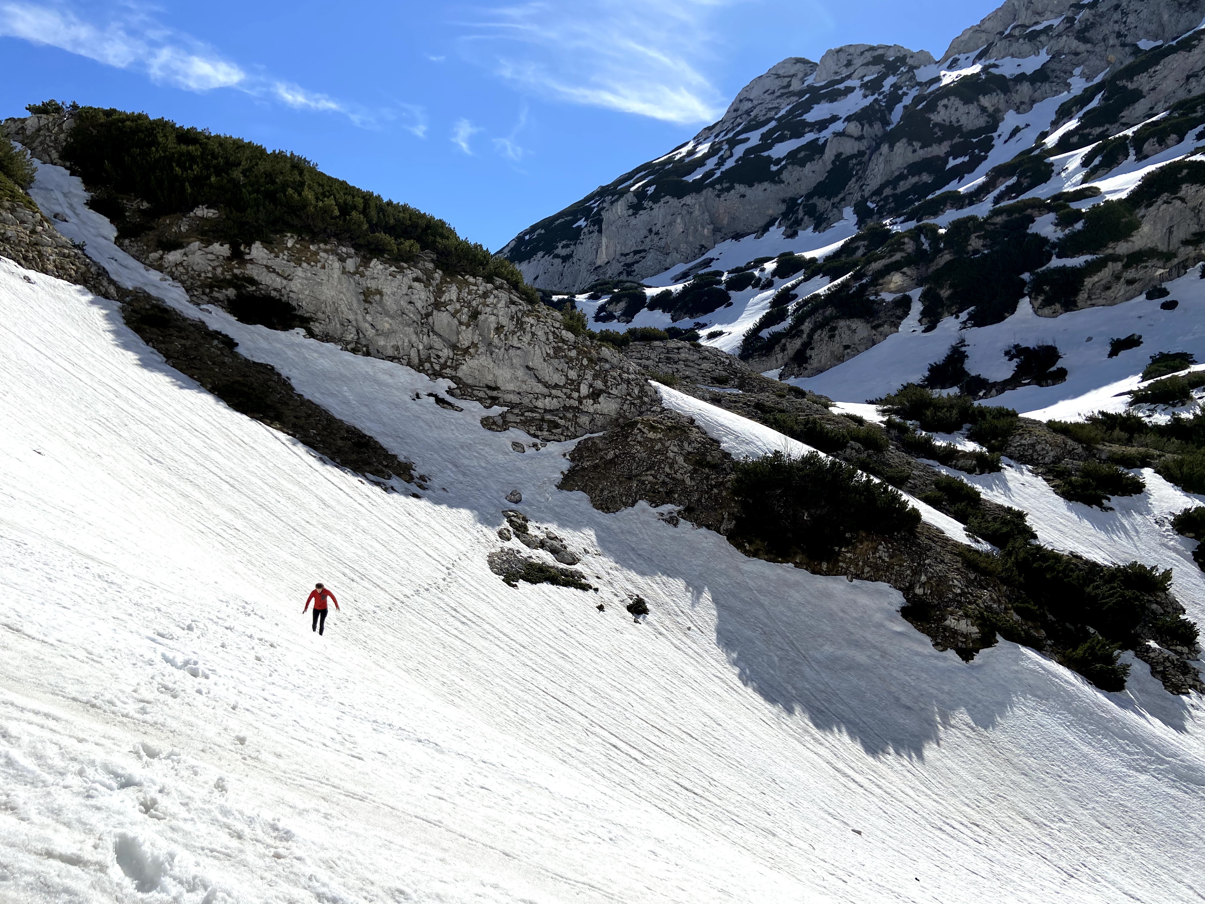 Woman travelling along the deep snow on Bobotov Kuk in Durmitor National Park. There is snow resting on the ledges everywhere.