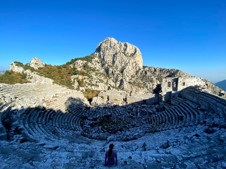 Woman sat in the grand amphitheatre with rock views surrounding.