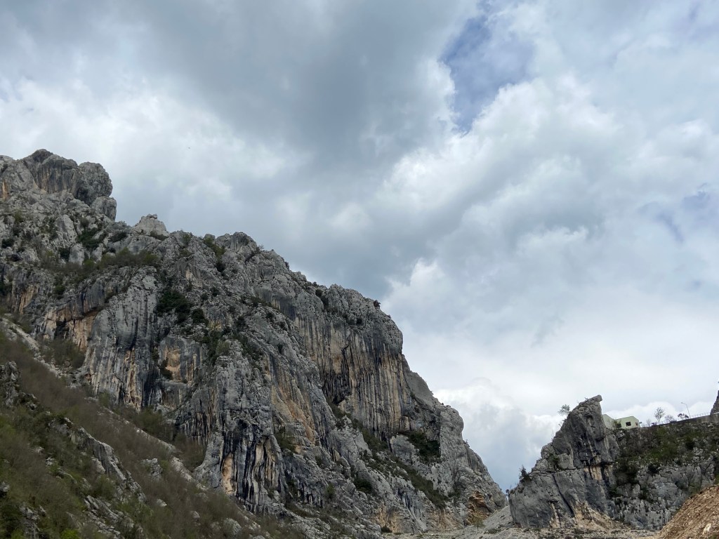 A mass of limestone crags, which sit on the side of a forested hill. 