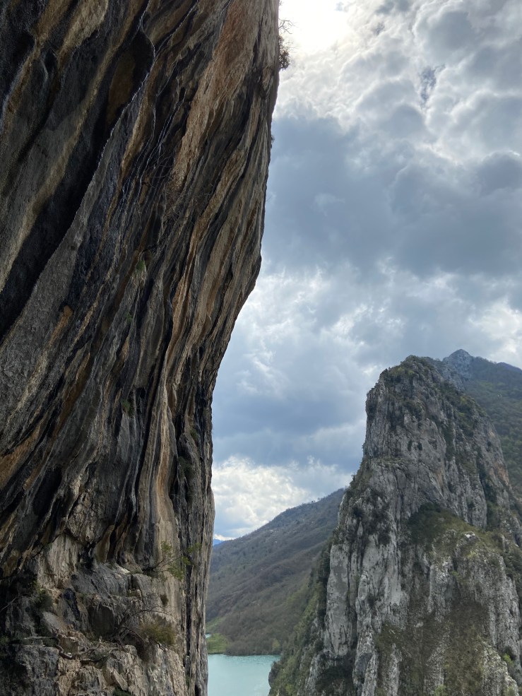 Steep limestone crag covered in tufas. In the background there are further craggy outcrops which sit upon the artificial lake.