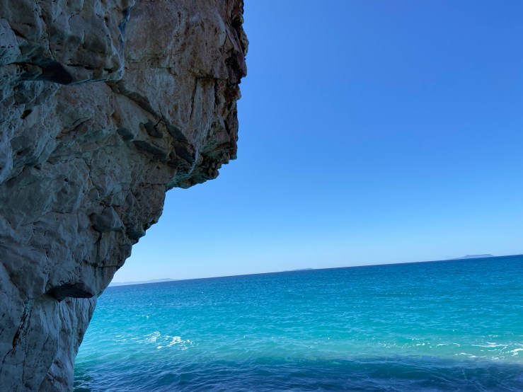 Limestone sea cliff, it is high tide and the water is lapping on the bottom of the crag. 