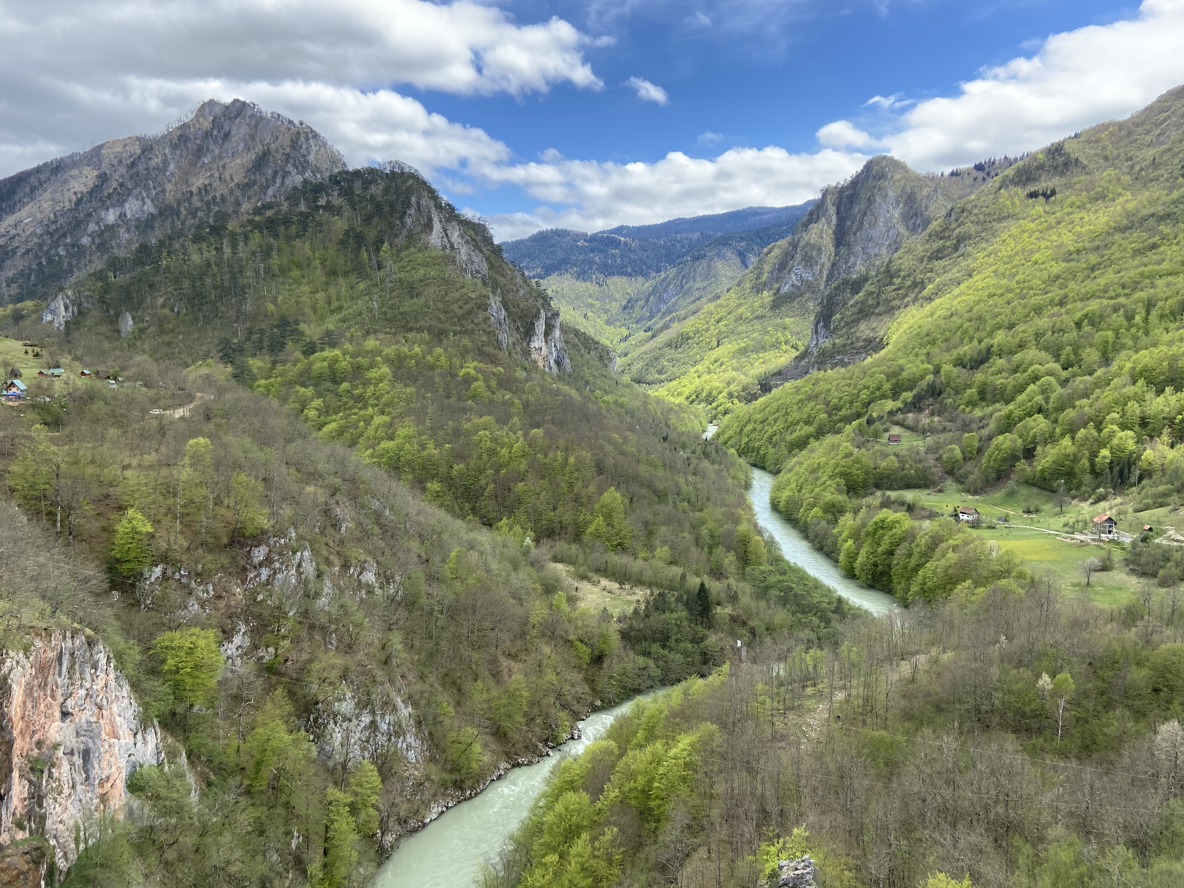 A lush green river canyon with mountainous sides and a gorgeous river below with a dog leg bend in it. 