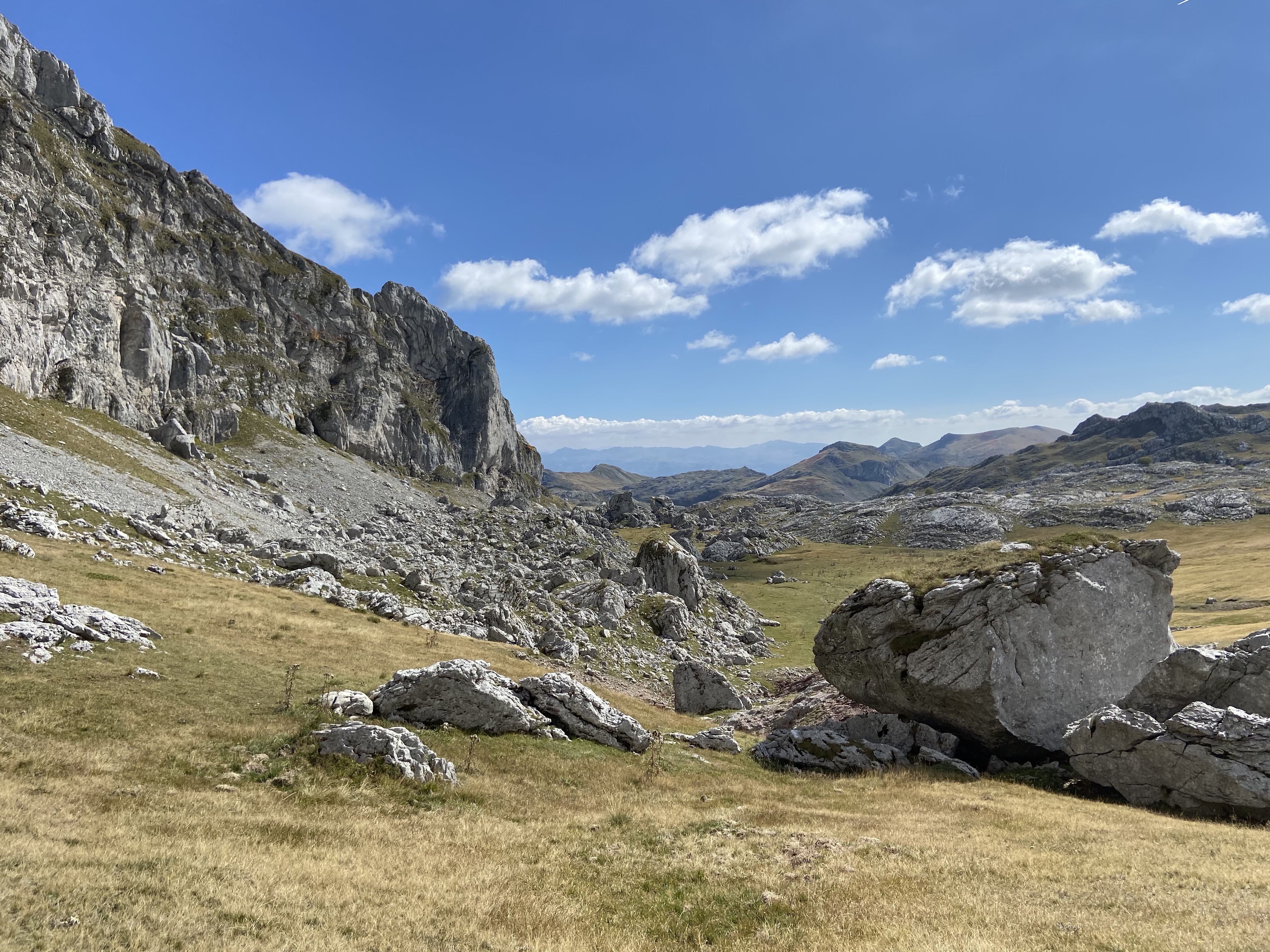 A stunning limestone boulder with a sheer face sits in a gorgeous green valley full of boulders and with great views. 