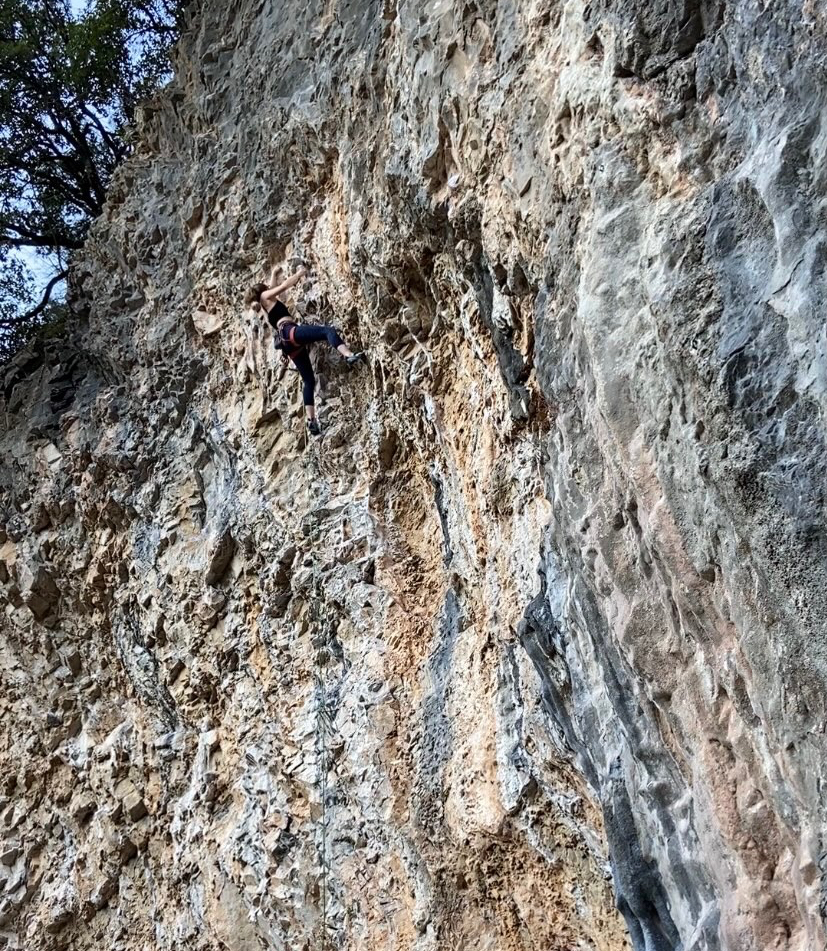 Climber a slightly overhang route on a  limestone cliff filled with tufas 