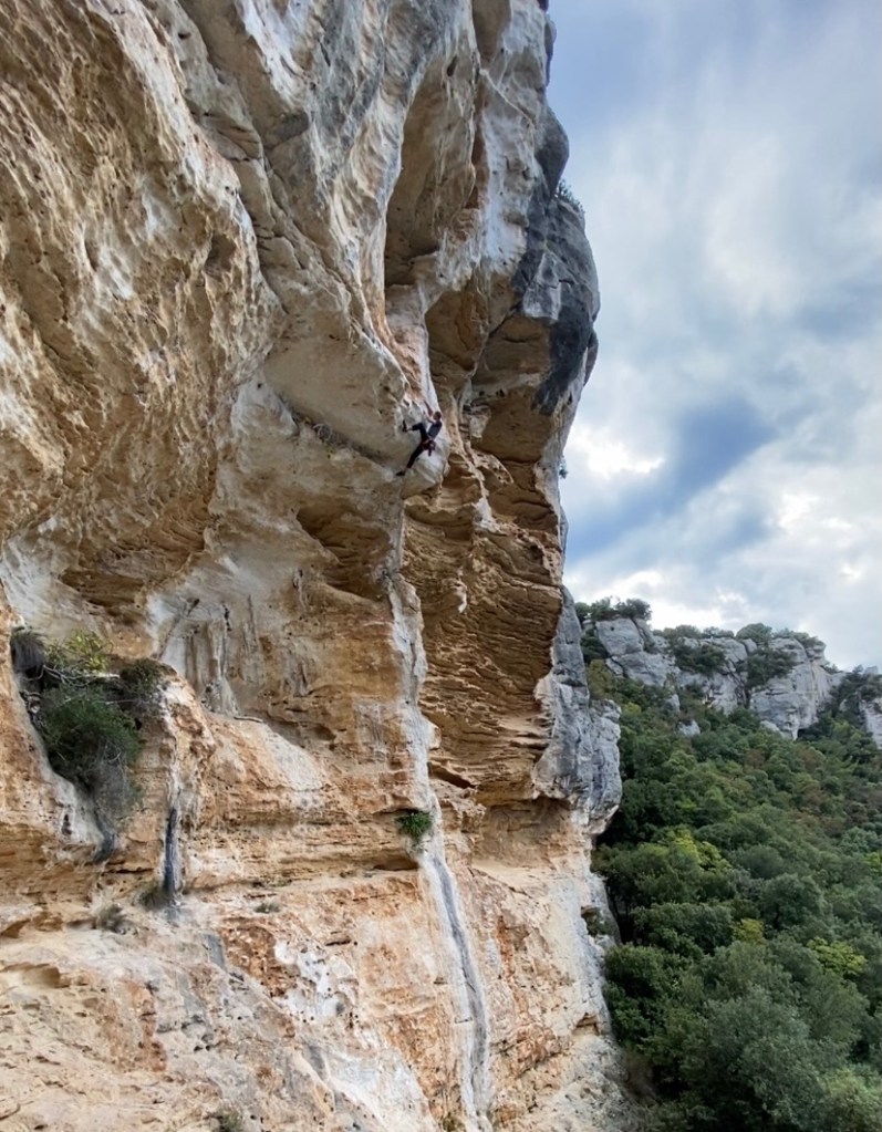 Climber tackling the steep climb on white and orange limestone.