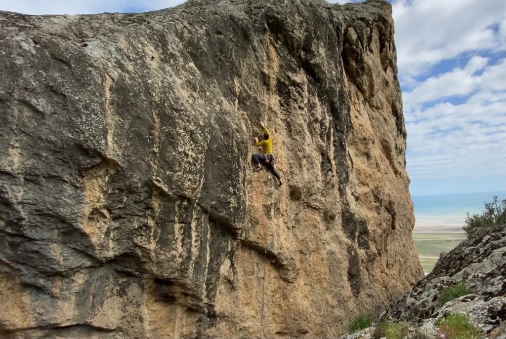 Climber on orange and black limestone boulder.