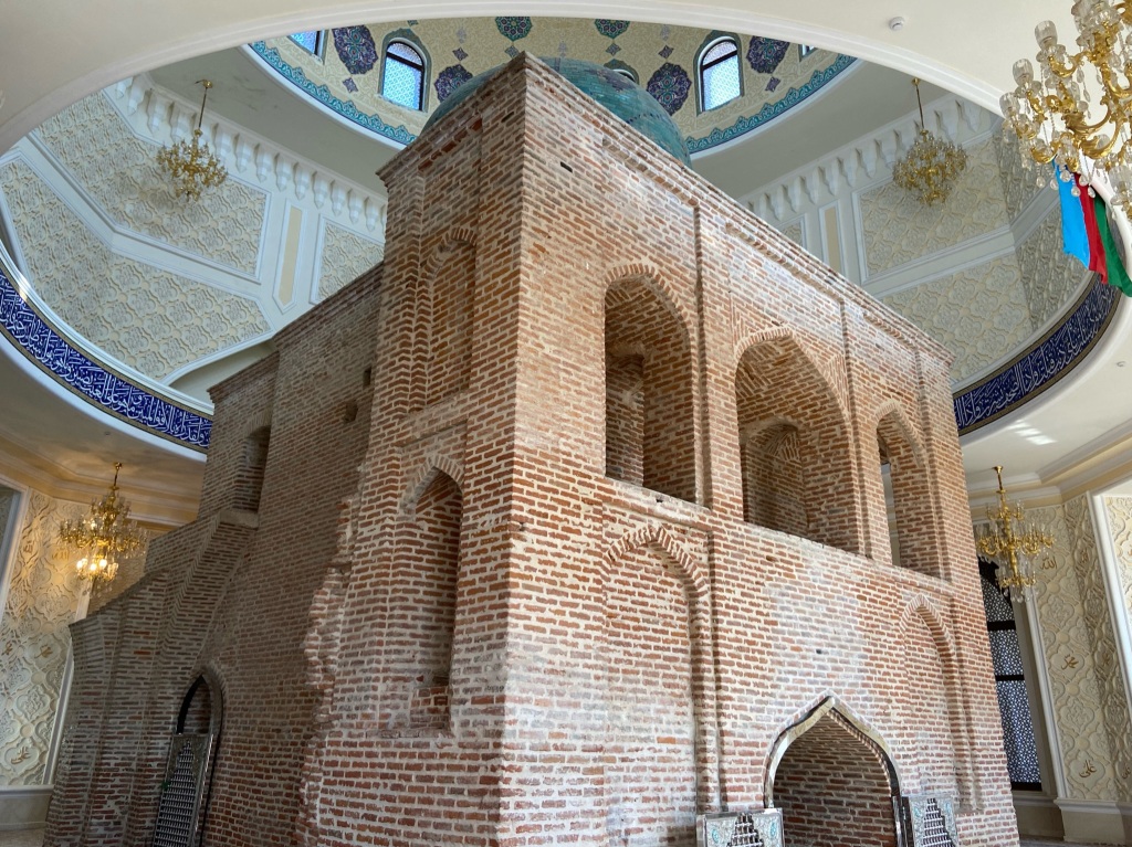 A mosque inside a mosque! An ancient red bright mosque with a blue tiled dome on top. Surround the old mosque is a new and elaborately designed new and modern mosque. 