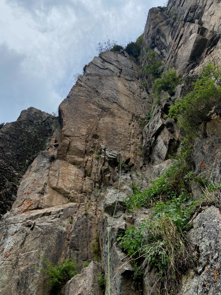 Climber at the top of a route which climbs a featured wall 