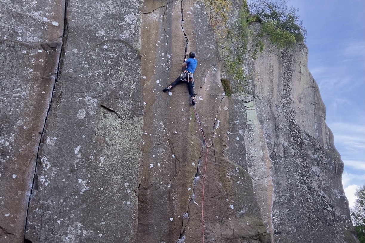 Climber working their way up a crack in the blank looking wall
