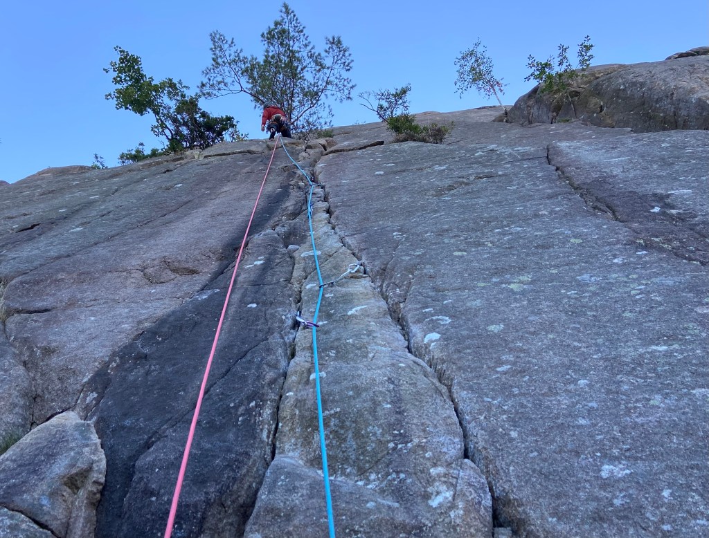 Cimber on the rock which has cracks breaking up the rock.