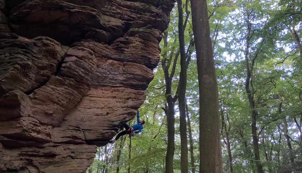 Climber on extremely steep and overhanging arête. The arête is broken with horizontal breaks which are the handholds. The climbers position shows the true steepness of the climb as they are at a 45 degree overhanging angle. 