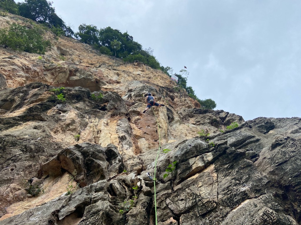 Climber bridging between a tufa and the wall on orange and white limestone
