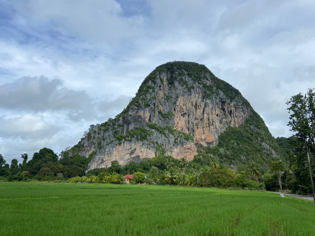 Large cliff of orange and gray rock in a hump shape.
