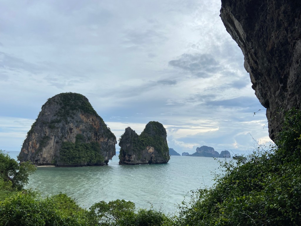 Two small limestone island cliffs which are surrounded by water with other islands in the distance.