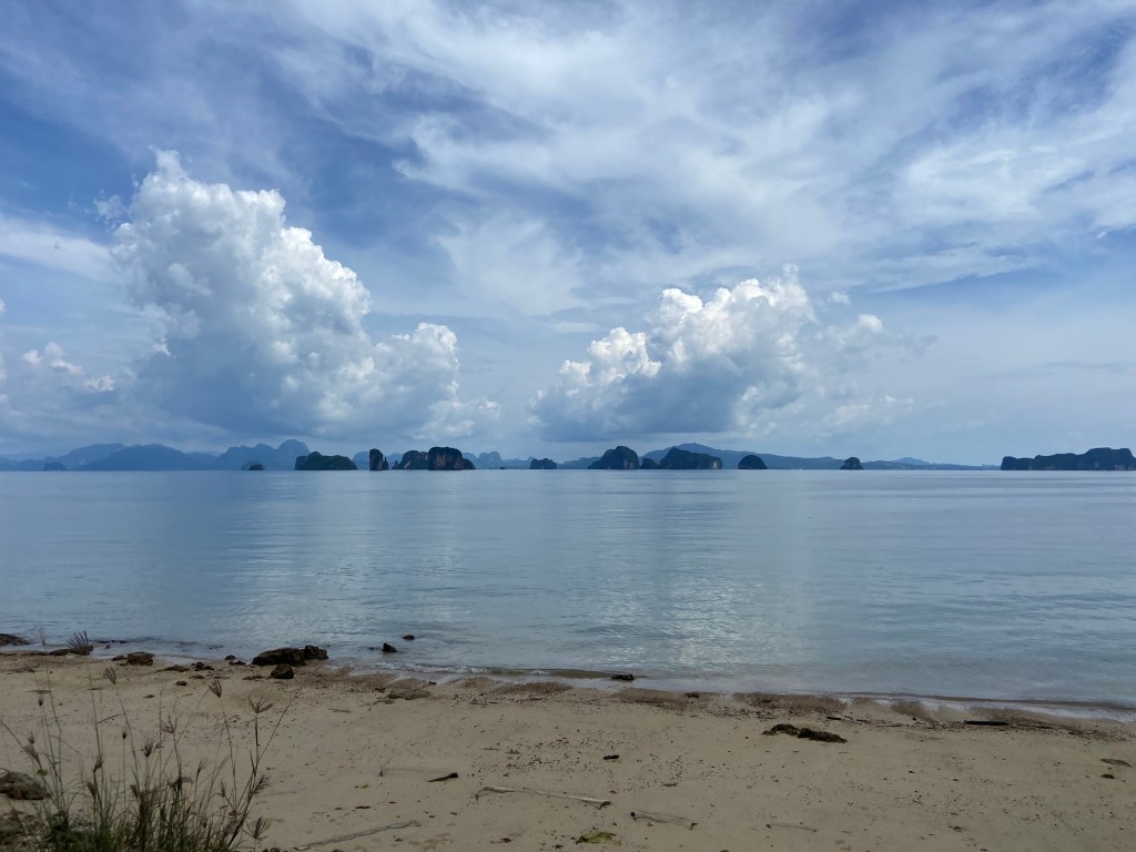 Looking from the beach on Koh Yao Noi towards the different cliff islands in the distance and behind them is the rocky and mountainous mainland of Krabi