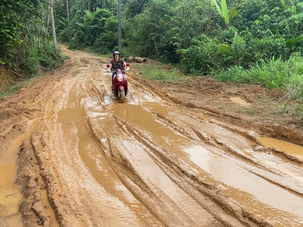 Woman on motorbike on a really muddy road through the jungle on Koh Yao Noi.