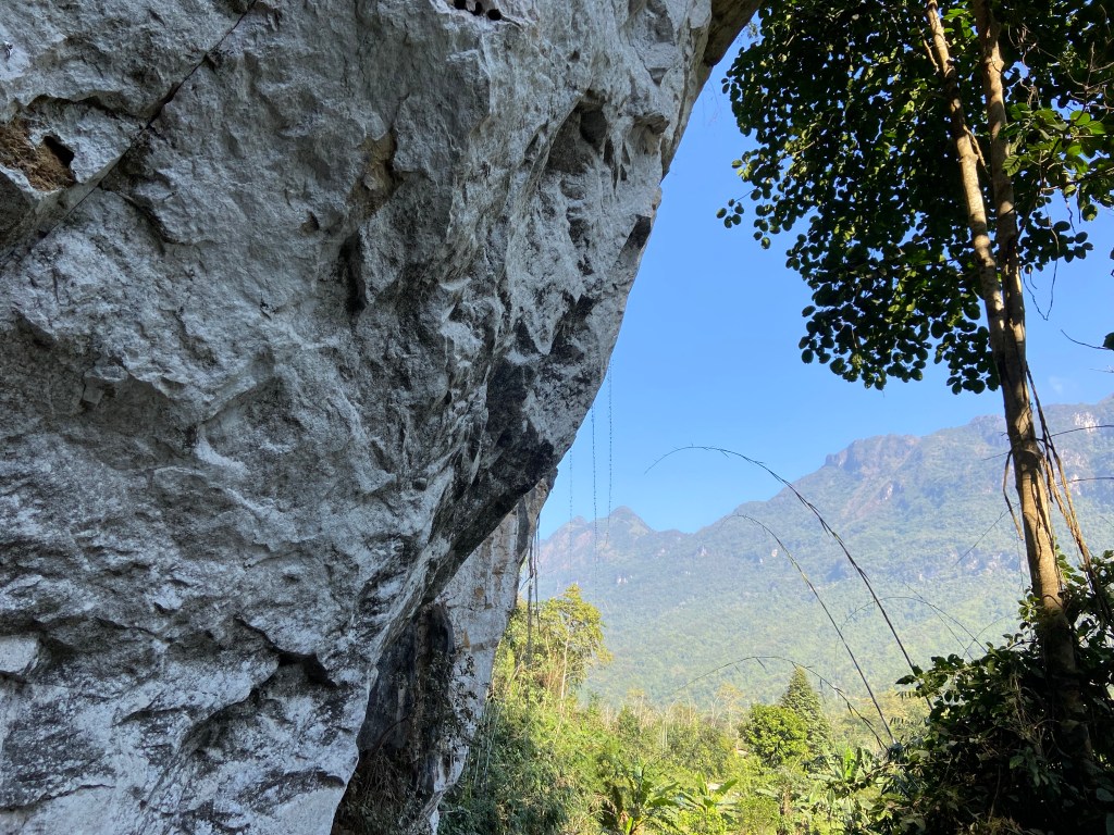 Overhanging white limestone cliff with a craggy mountain in the background