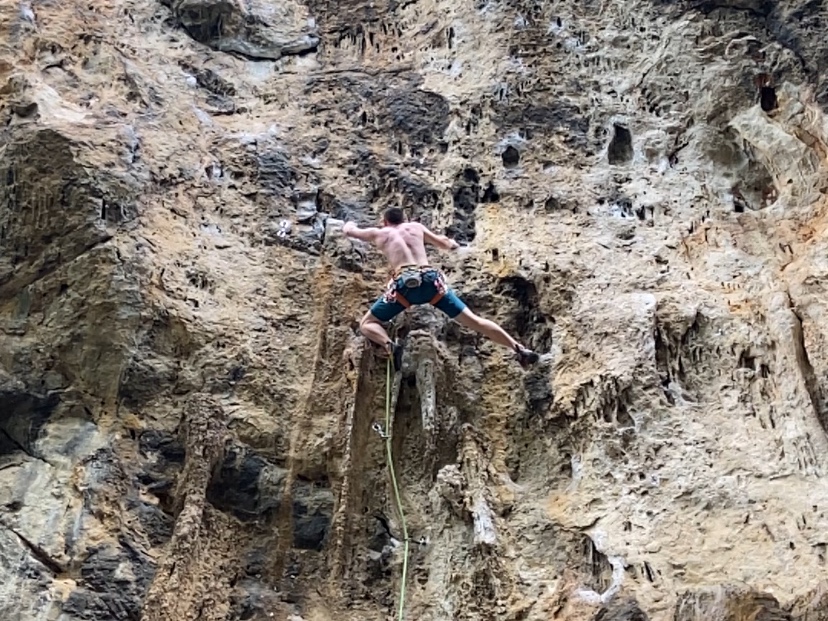 Climber making their way up the tufas and features on the white and black limestone cliff at Crazy Horse Buttress