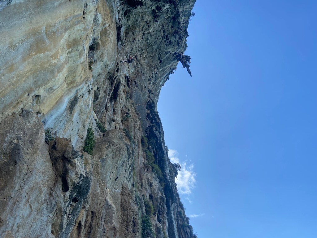 Climber abseiling off a steep limestone wall of sector Tonsai Wall that has tufas hanging off which empathises the steepness and size.