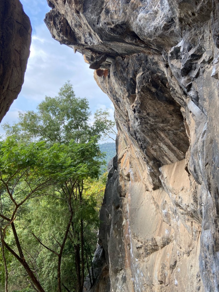 grey and creamy orange limestone cliff with Chalk marks which highlight where the routes are at Crazy Horse Buttress