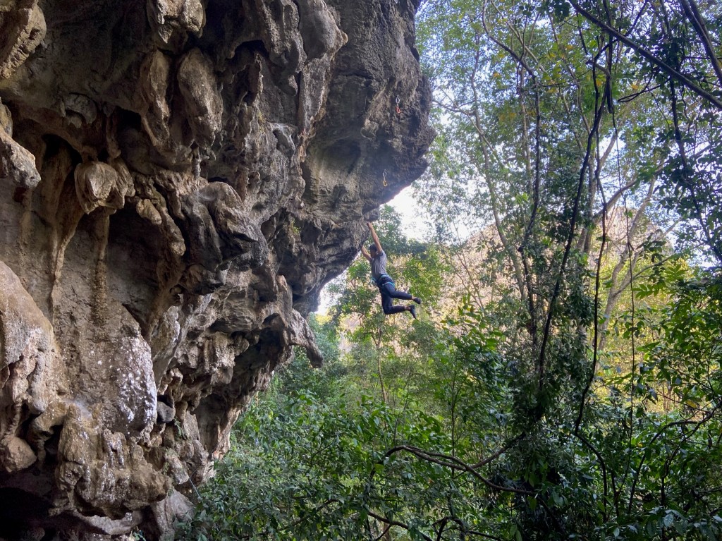 Climber cutting loose on overhanging, tufa rich limestone cliff of S&M