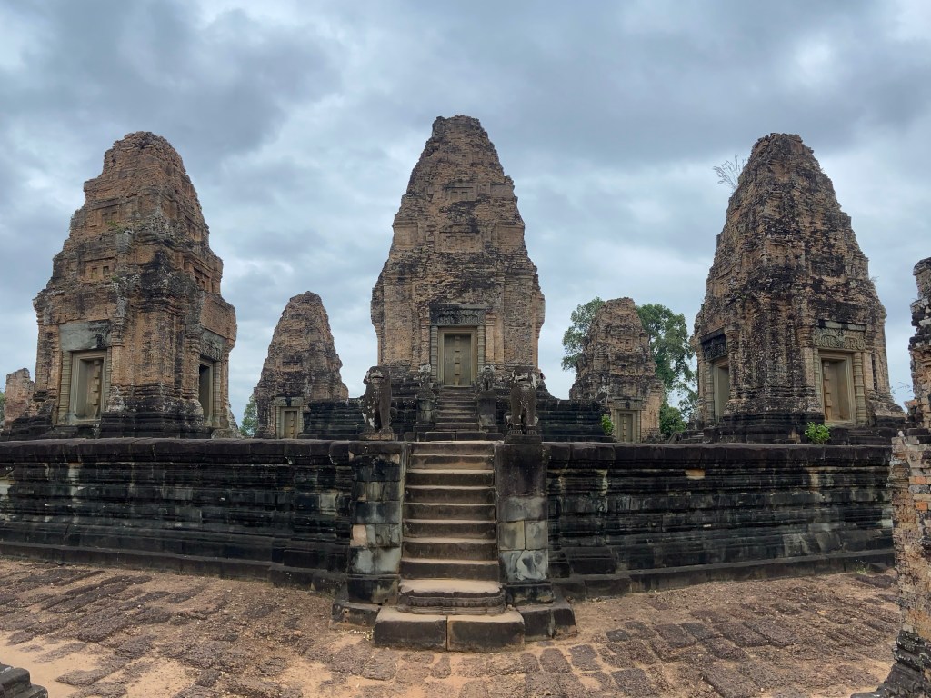 Ancient temple with five towers arranged like a five on a dice. They're made from dark laterite stone with a staircase leading up to them