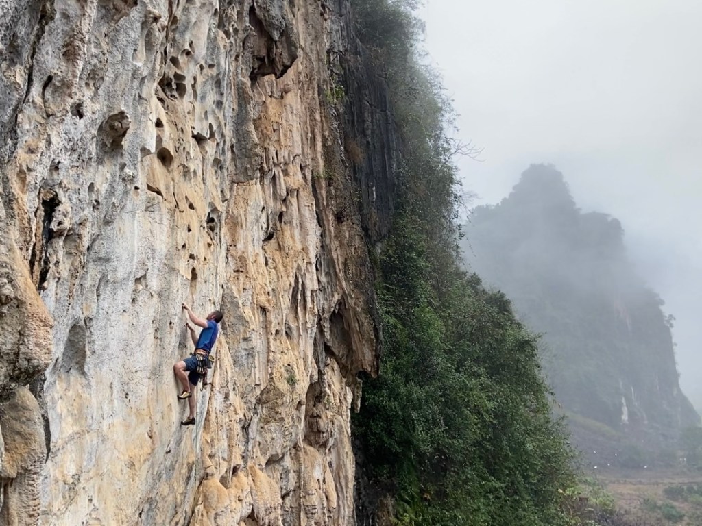Climber on white limestone rock at Head Wall, Hữu Lũng. The weather is misty 