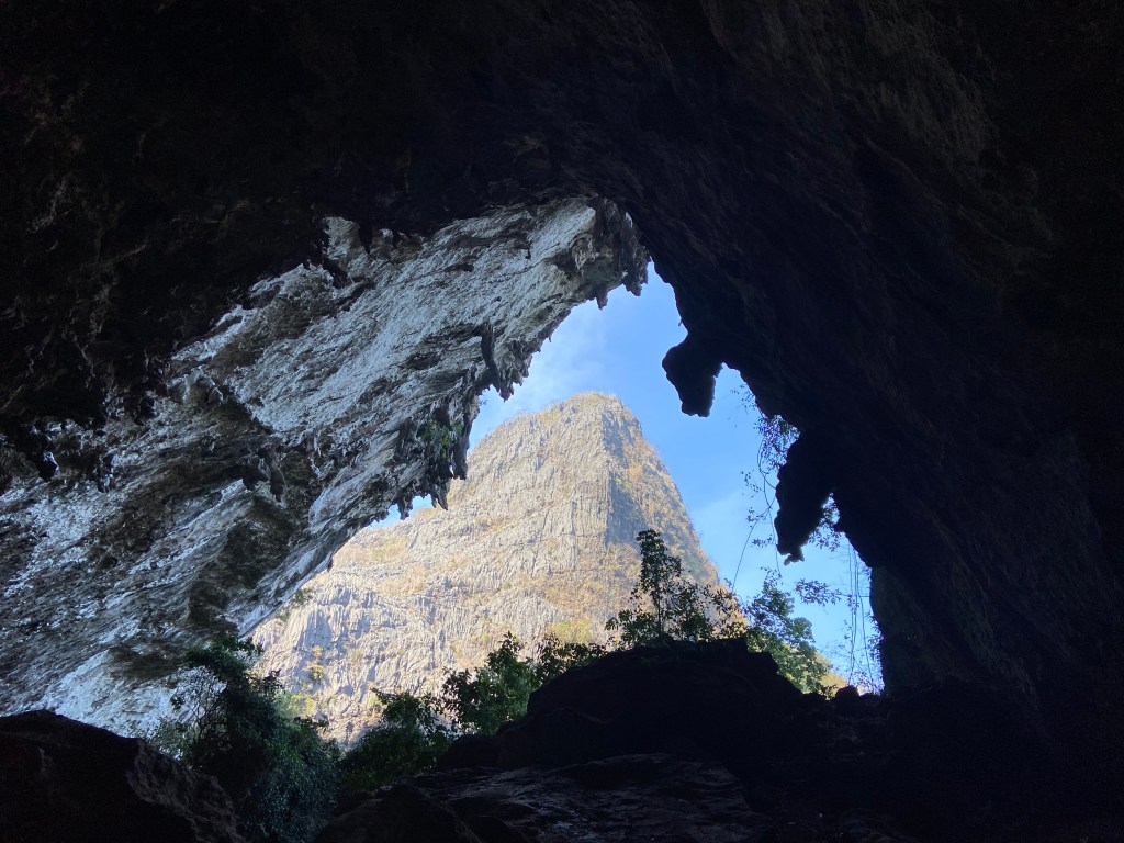 Looking out from inside the cave the roof has large tufas hanging from the steep but blank walls. On the Other side of the valley is another, not so compact limestone mountain. 