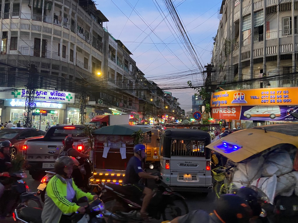 Chaotic city cross road gridlocked with motorbikes, tuk-tuks, cars and pick up trucks.