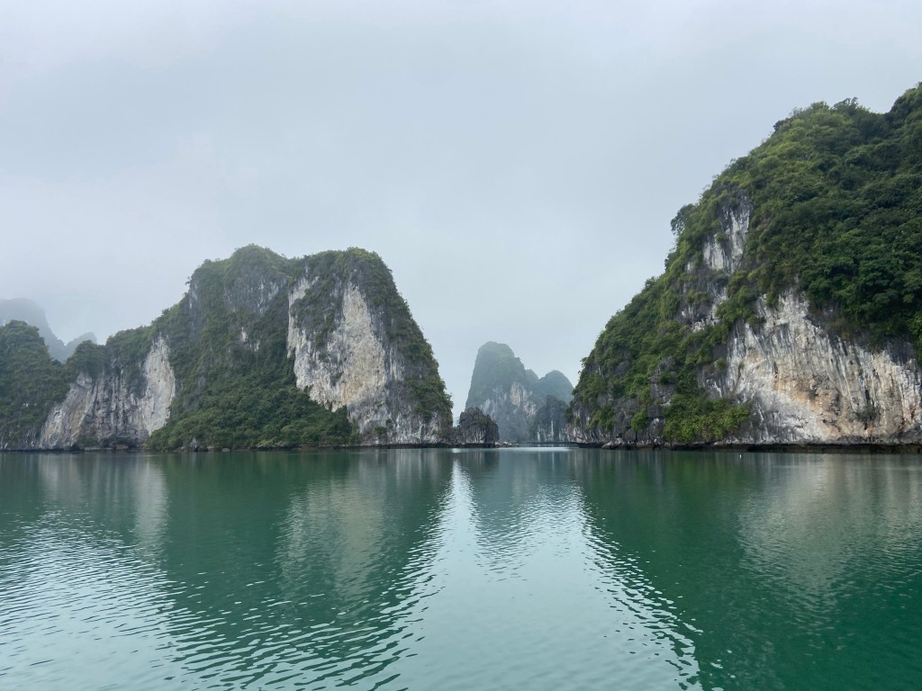 Craggy limestone mogotes rising from the green sea to form islands dotted in the bay.