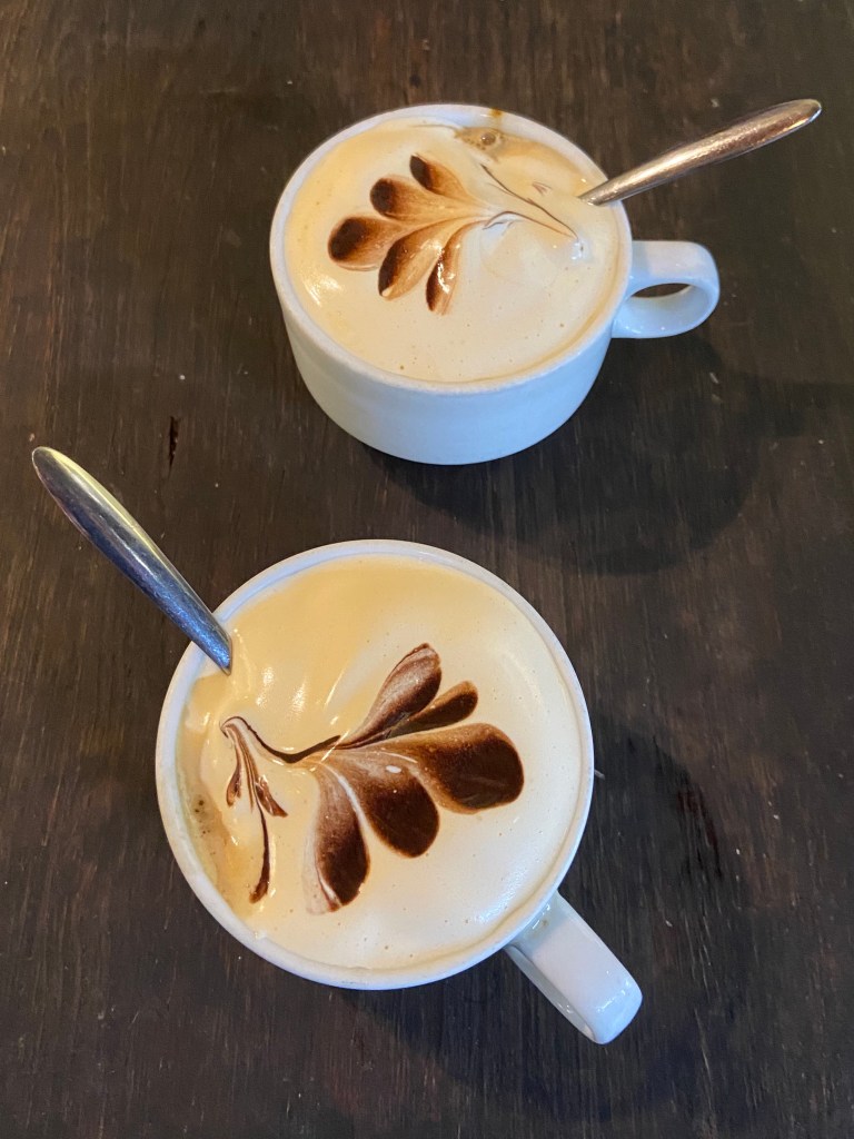 Two cups with foamy egg cream on top with a design from the coffee on top.