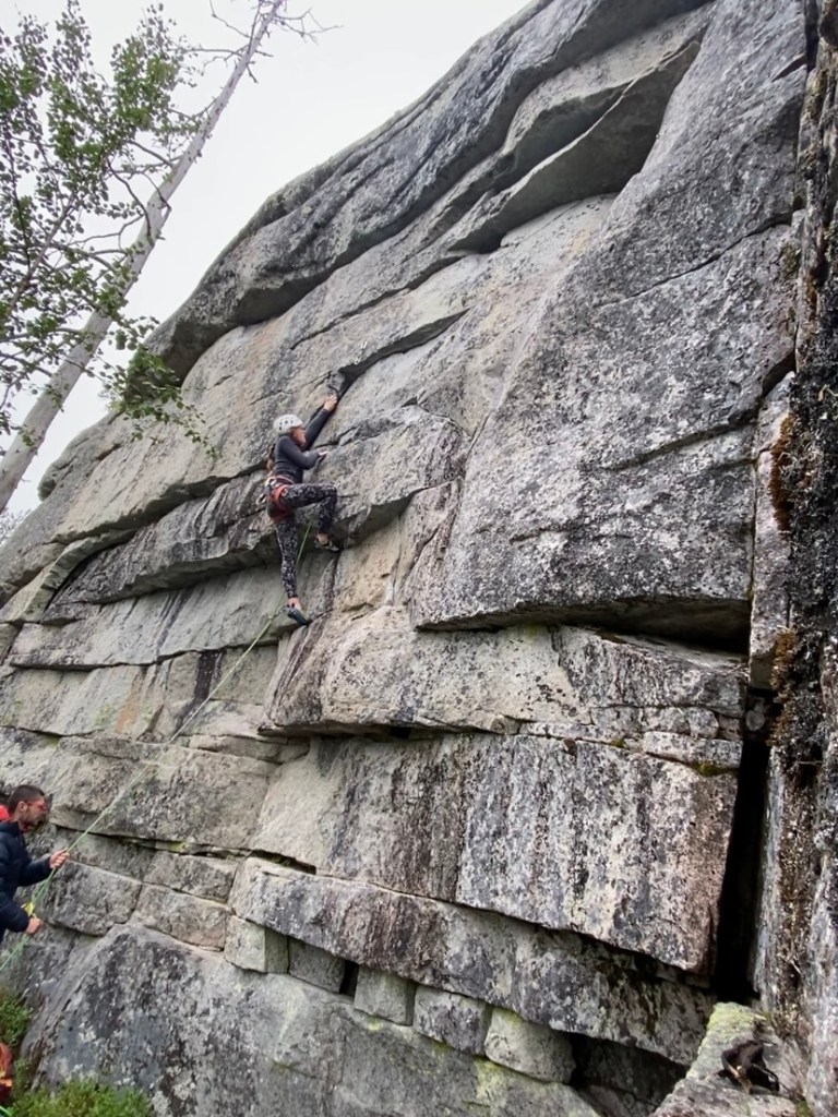 Climber reaching up for a high handhold on a short granite wall