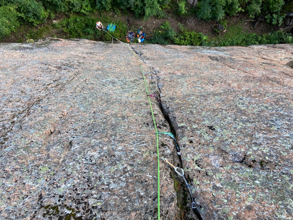 Looking down the crack climb down to the forest and belayer below. The crack of slim and slopey and it has tranditional gear placed inside the crack
