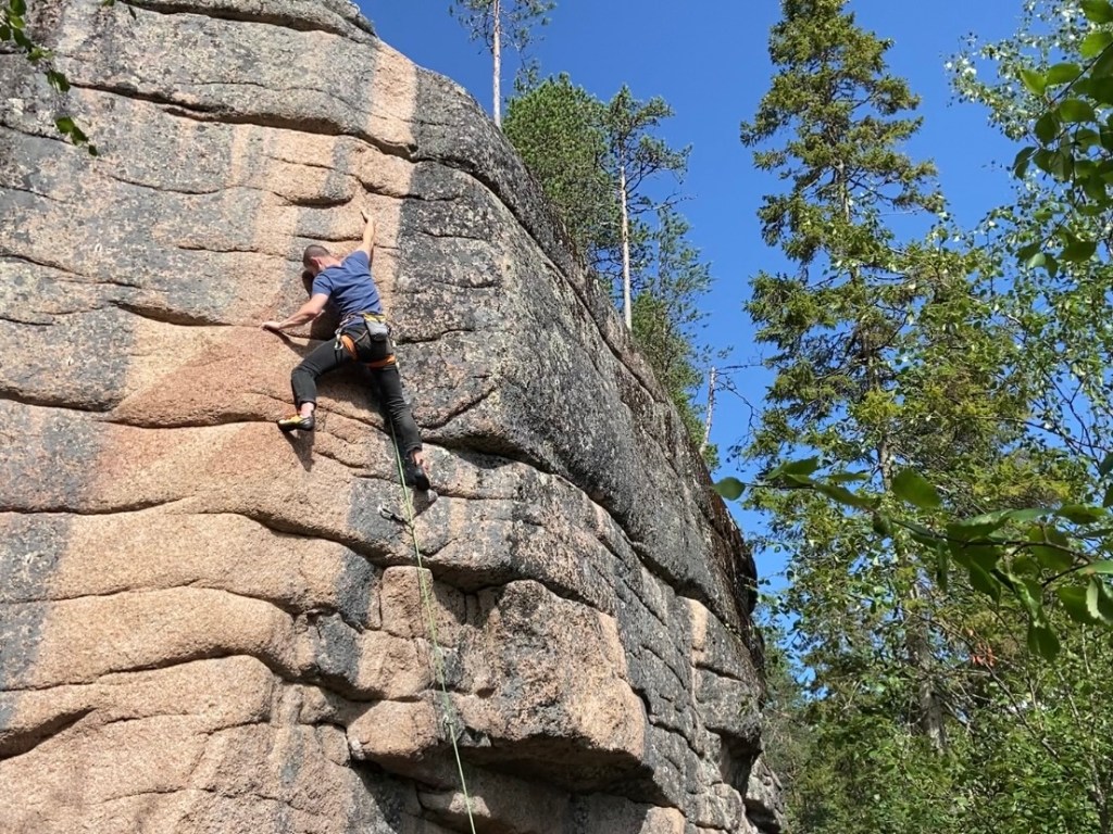 Climber using the horizontal crack features on the smooth pink and grey granite walls