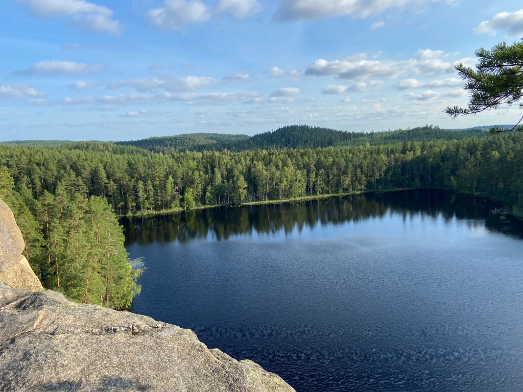 Looking out from the top of the granite crag over a lake with forested hills behind
