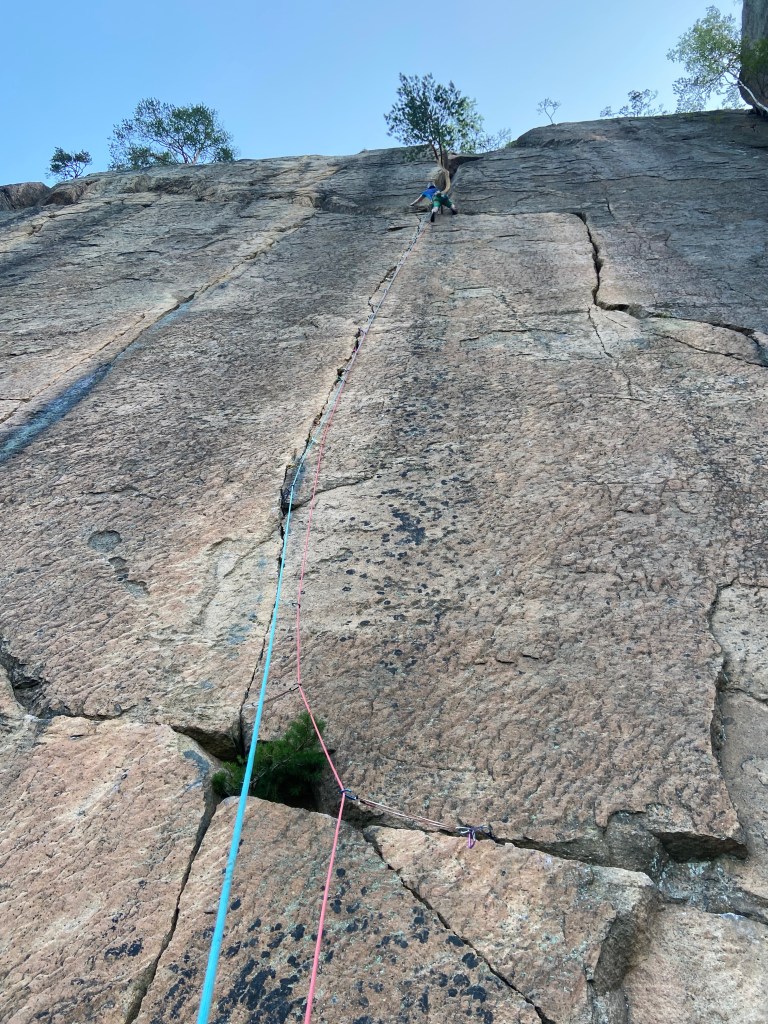 Climber working their way up a thin crack which has trad gear in it.