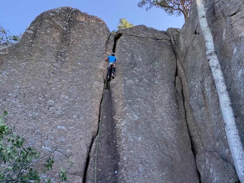 Climber working their way up the wide granite crag which requires the whole body and mind!