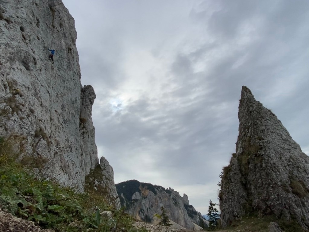 Climber among a sea of pale limestone surrounded by smaller pinnacles of rock and a large crag in the distance. 