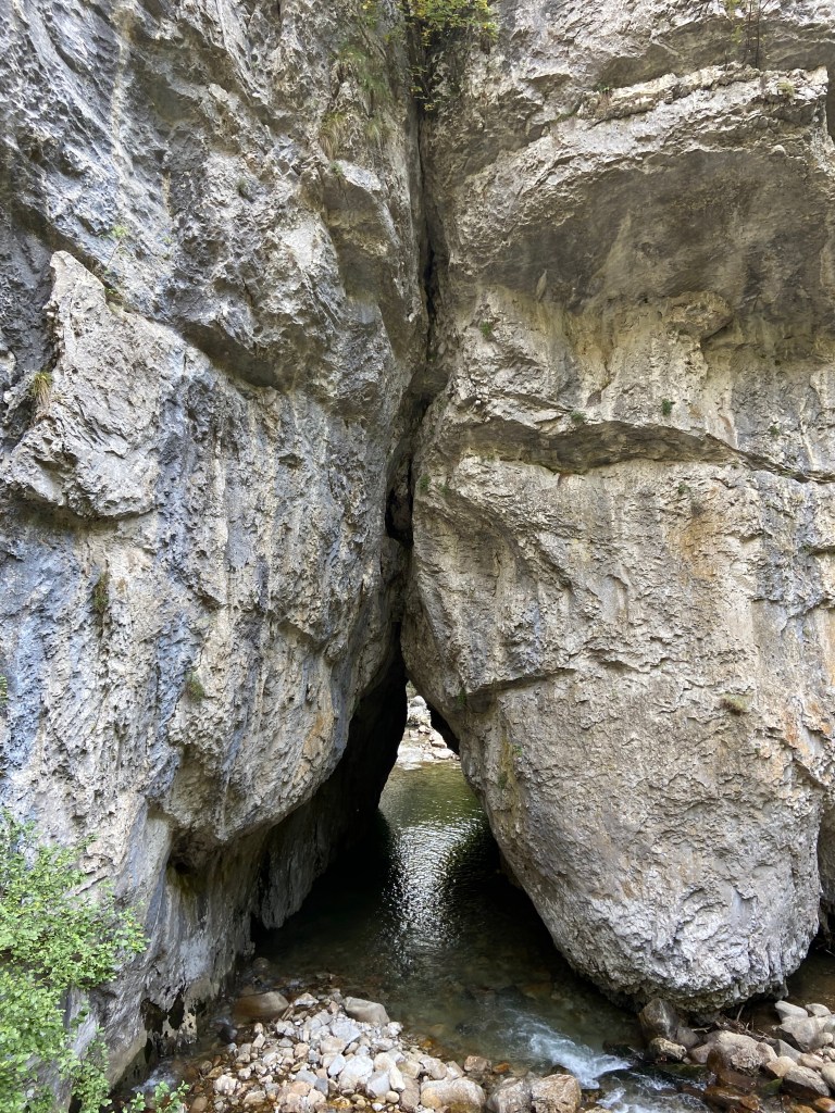 River running towards two sections of limestone rock, with grey and blue streaks running down it.