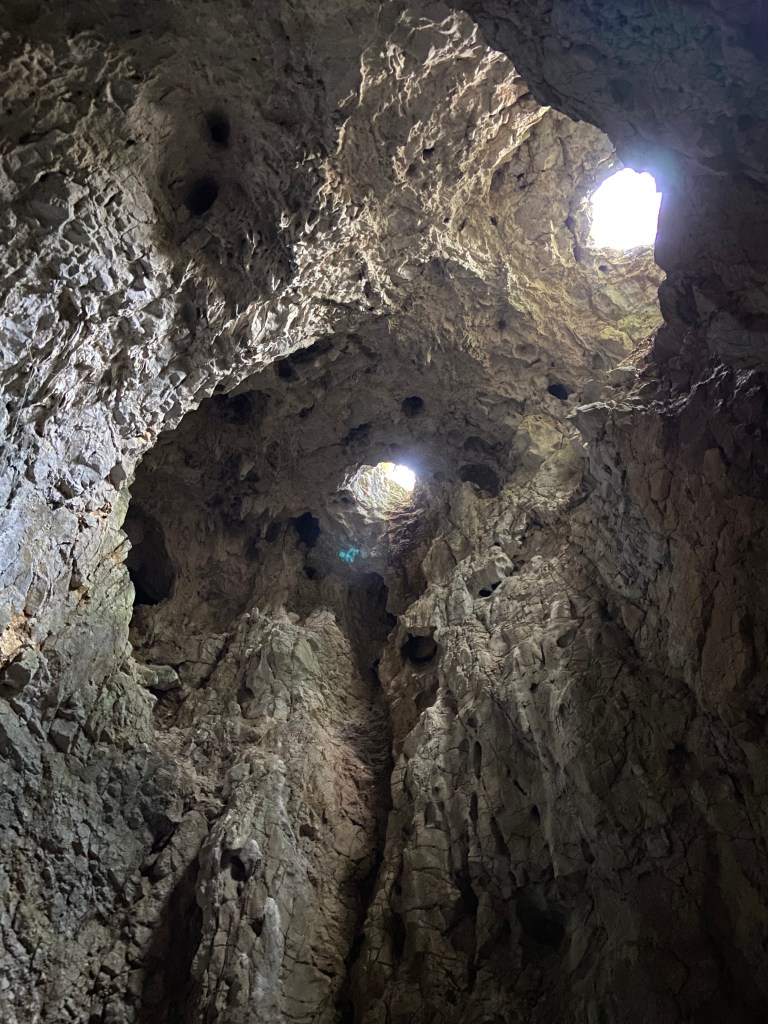 Cave roof which has two eye like holes which the daylight is streaming into the white limestone cave. 