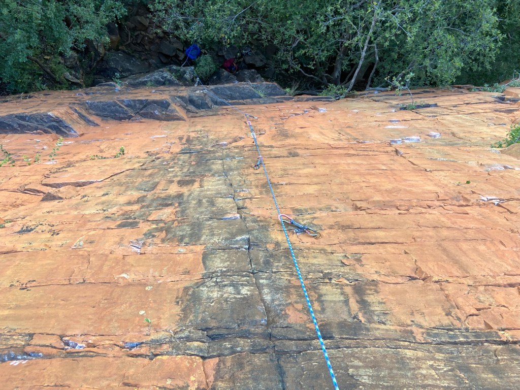 A view from the top of a vertical wall with the rope following a vertical crack feature.
