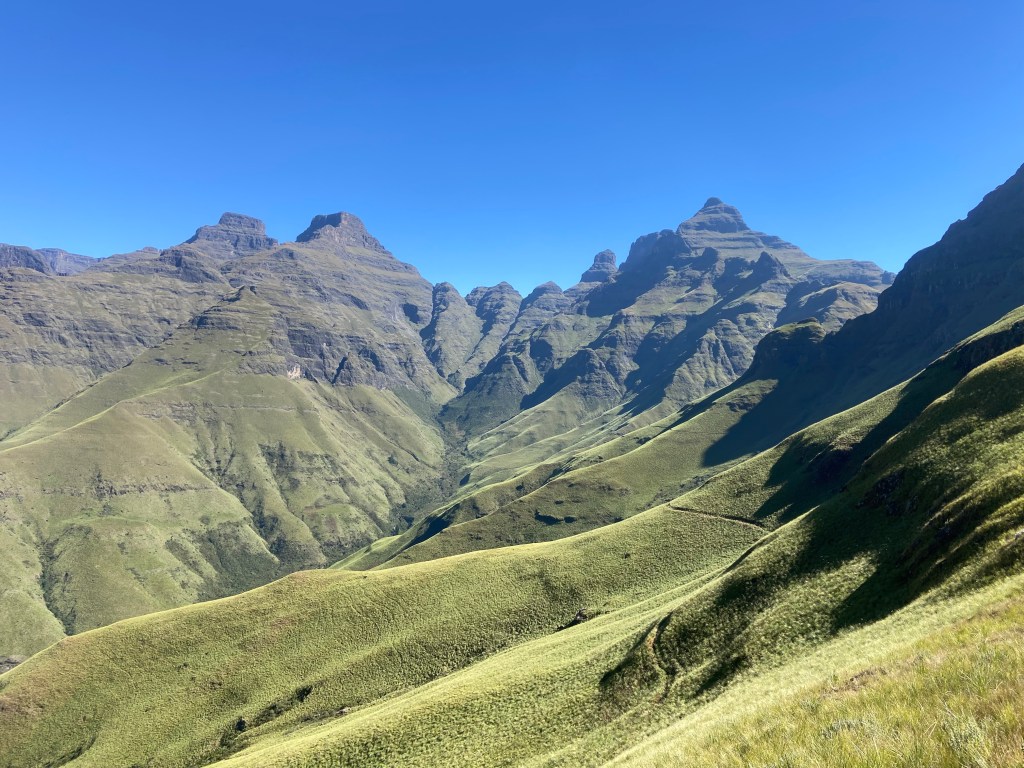 Lush green mountains with deep valleys and rocky, pointy peaks. 