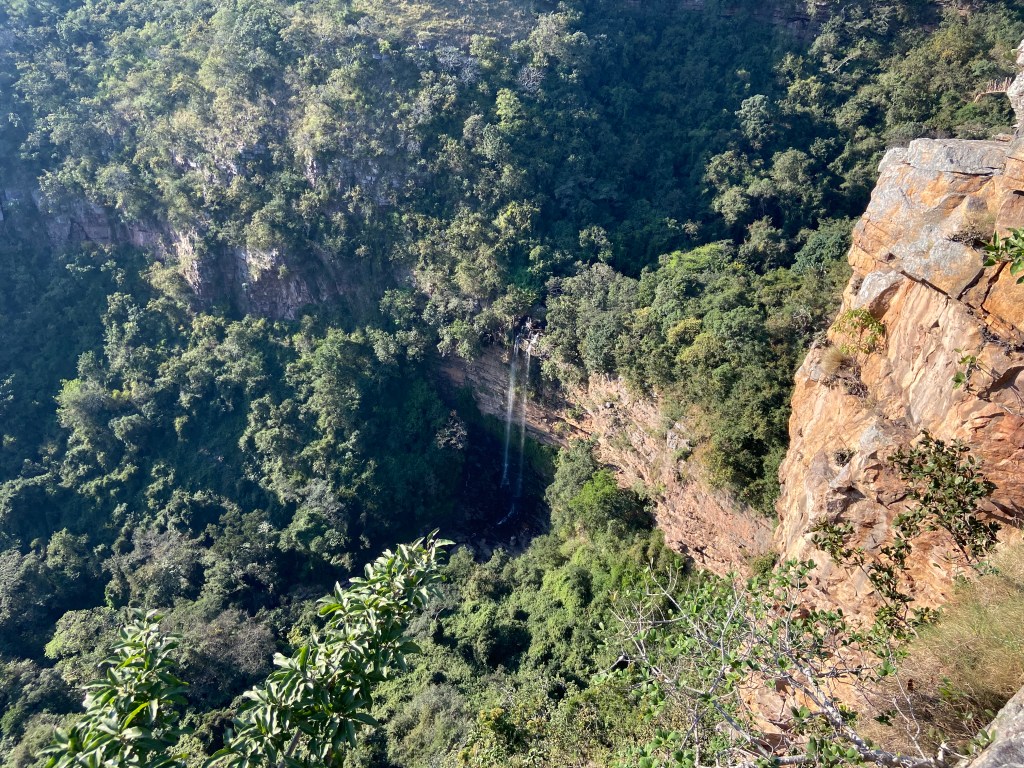 Steep cliffs emerging from the dense jungle with a waterfall in the centre. 