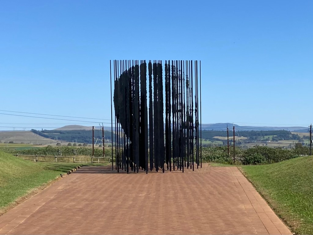 A sculpture of Nelson Mandelas face made with 50 different vertical pieces of metal which outline his features. 