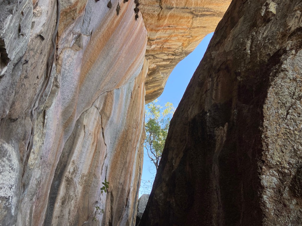 Rainbow granite in a slot canyon with blue sky peaking through in the background. 