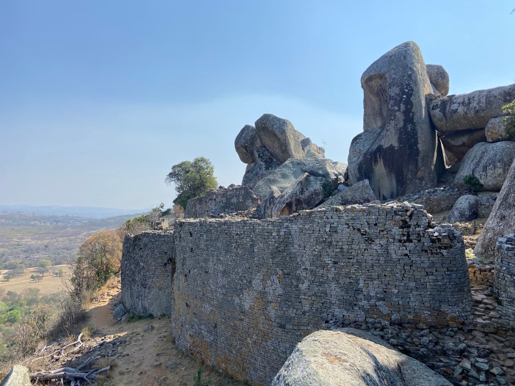 Stone wall built around huge granite boulders on top of a hill. 