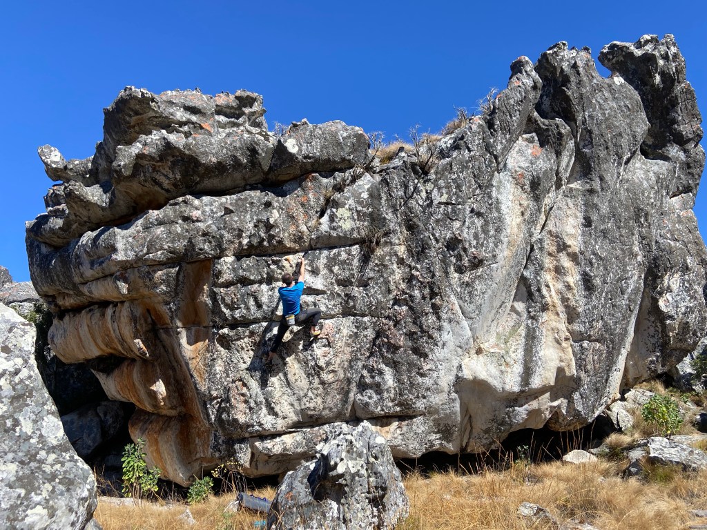 Climber on a giant quartzite boulder with colours of white and grey.